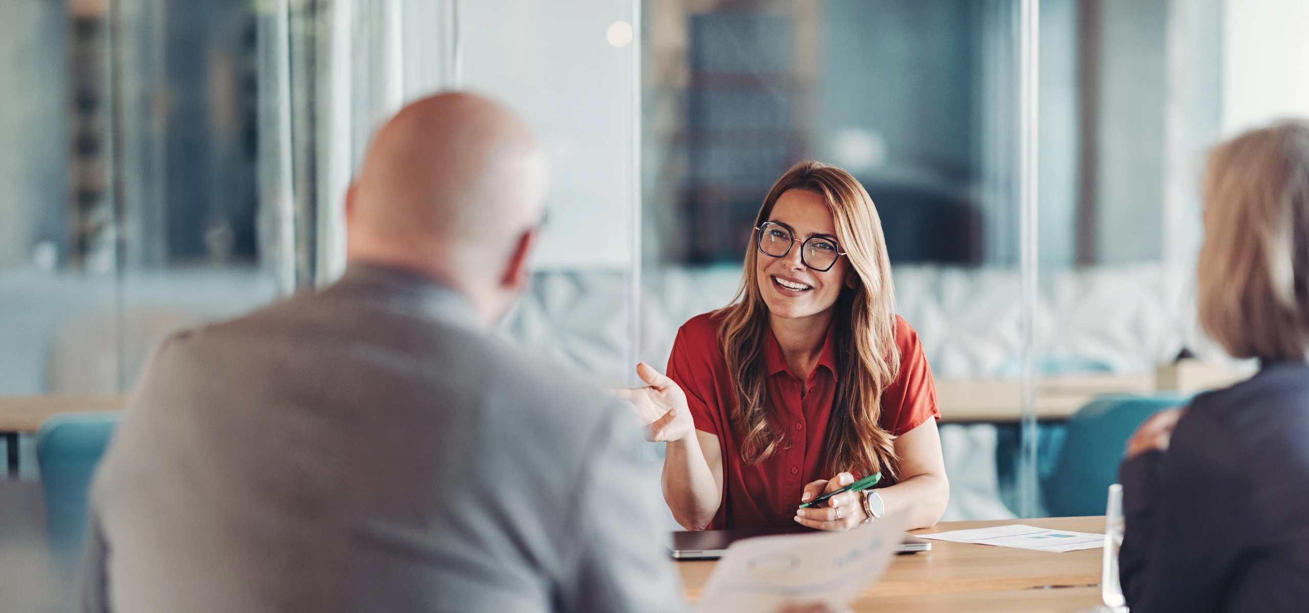 Person sitting at a table, gesturing while speaking during a business meeting.
